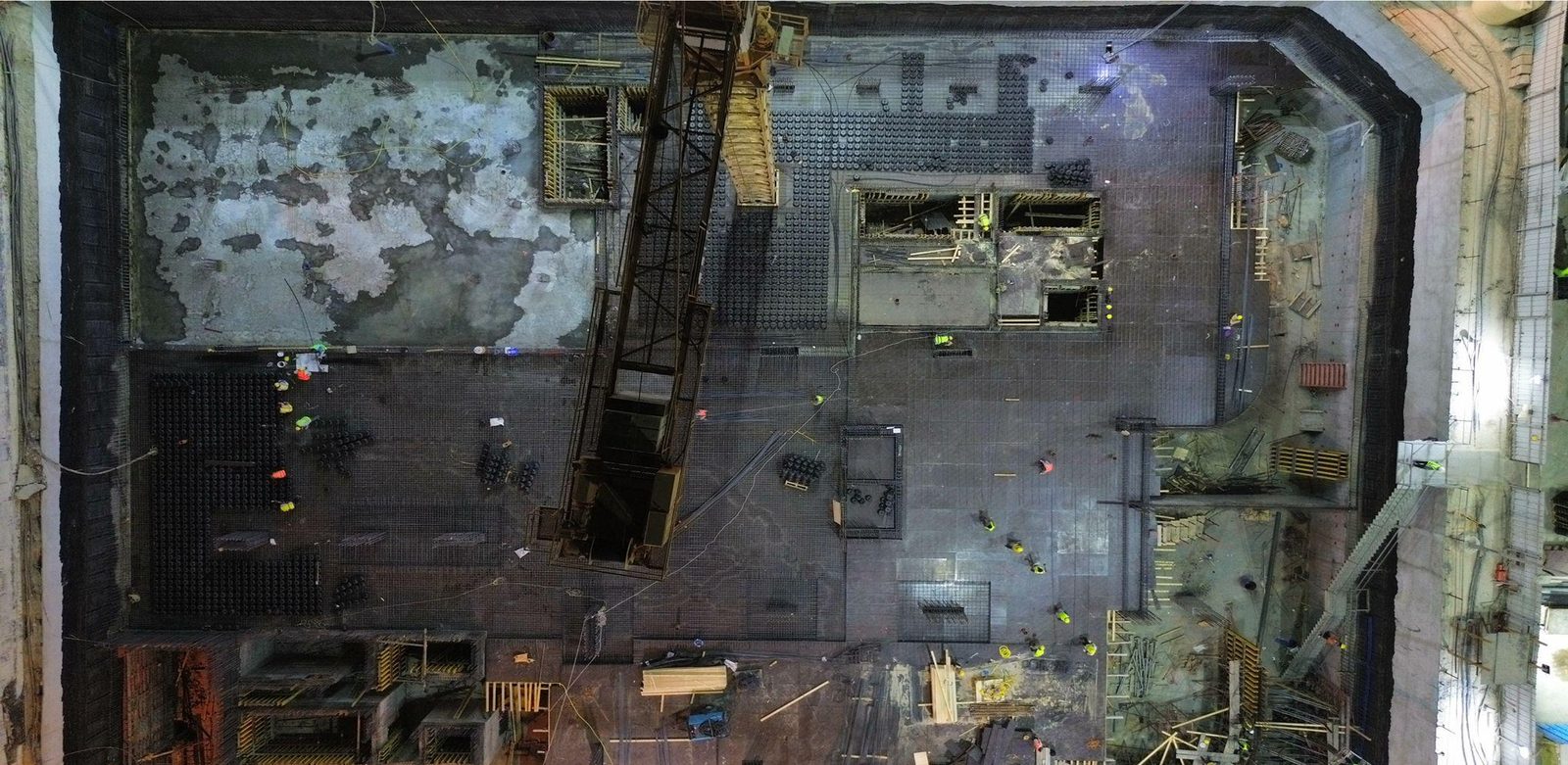 A construction site seen from above: the foundation slab, formwork and a tower crane